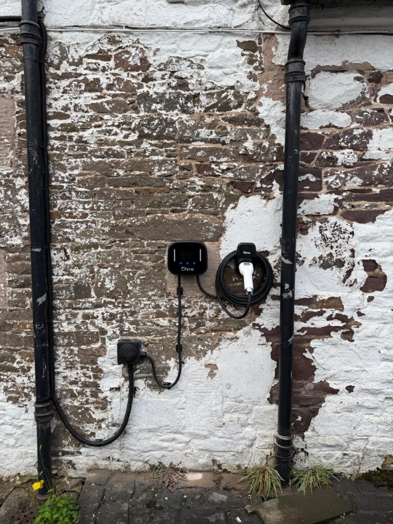 Ohme Home Pro EV charger with cable holder installed on an external stone wall in Thankerton by Renew-able Solutions