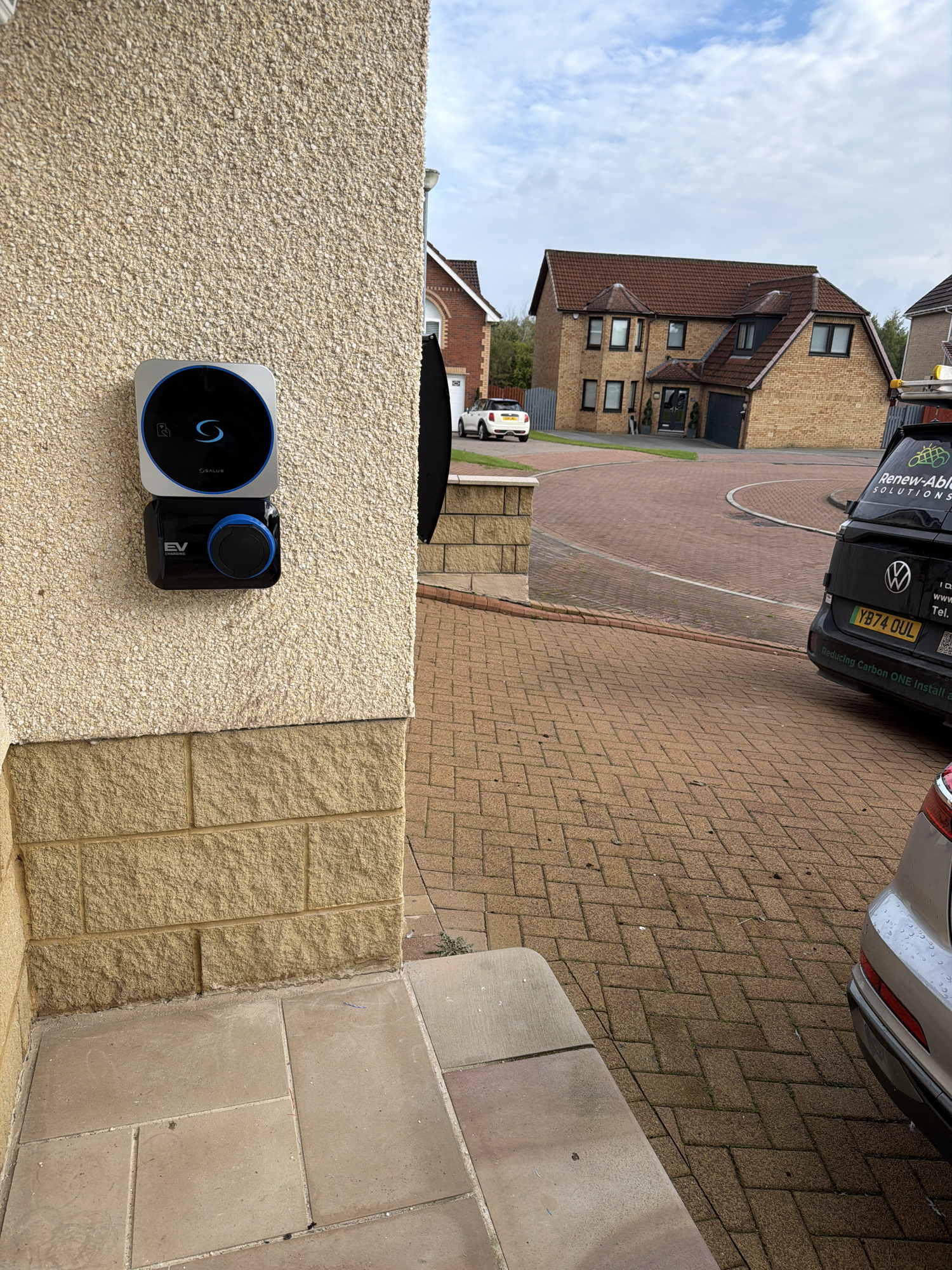SALUS EV7UK charger neatly mounted on an exterior wall beside a driveway in Glasgow